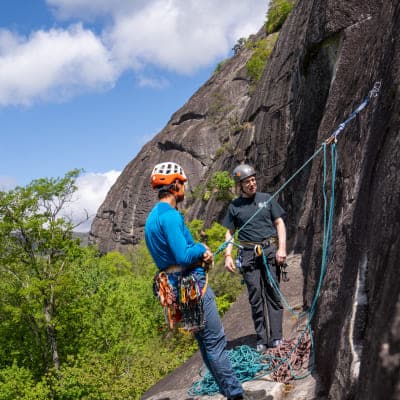 Karsten Delap and male rock climber rest harnessed to the edge of Looking Glass mountain
