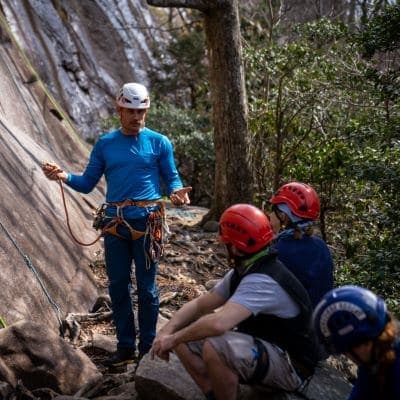 Karsten Delap provides group instruction to rock climbers sitting nearby
