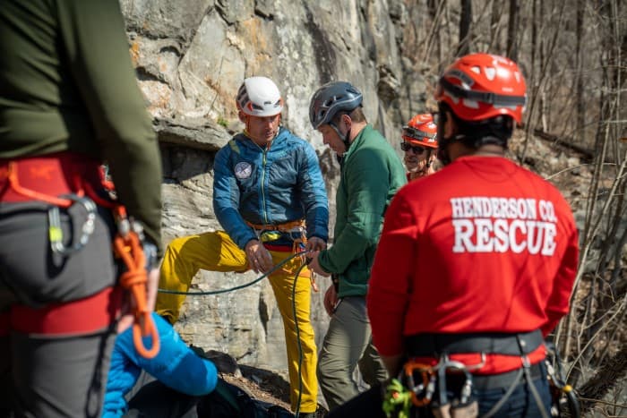 Delap helps henderson county rescuer rope in during rock climbing rescue training while other rescuers look on