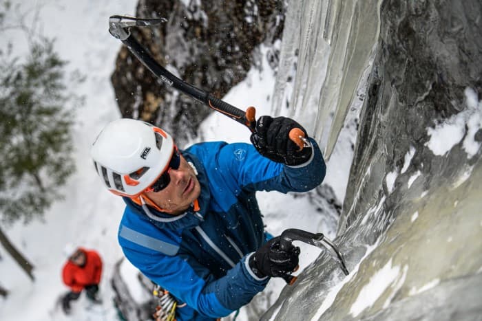rock climber Karsten Delap drives petzl ice ax into the ice while ice climbing in New Hampshire